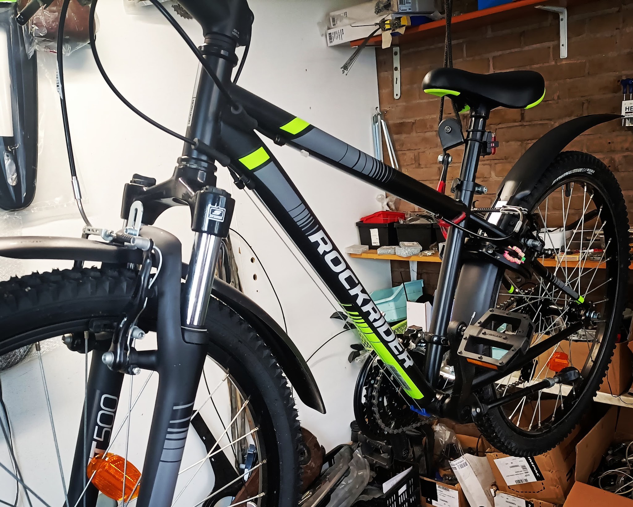 Een mountainbike op de werkplaatsstandaard, met schappen vol onderdelen op de achtergrond